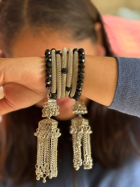 Close-up of a person wearing a bracelet and earrings with intricate designs.